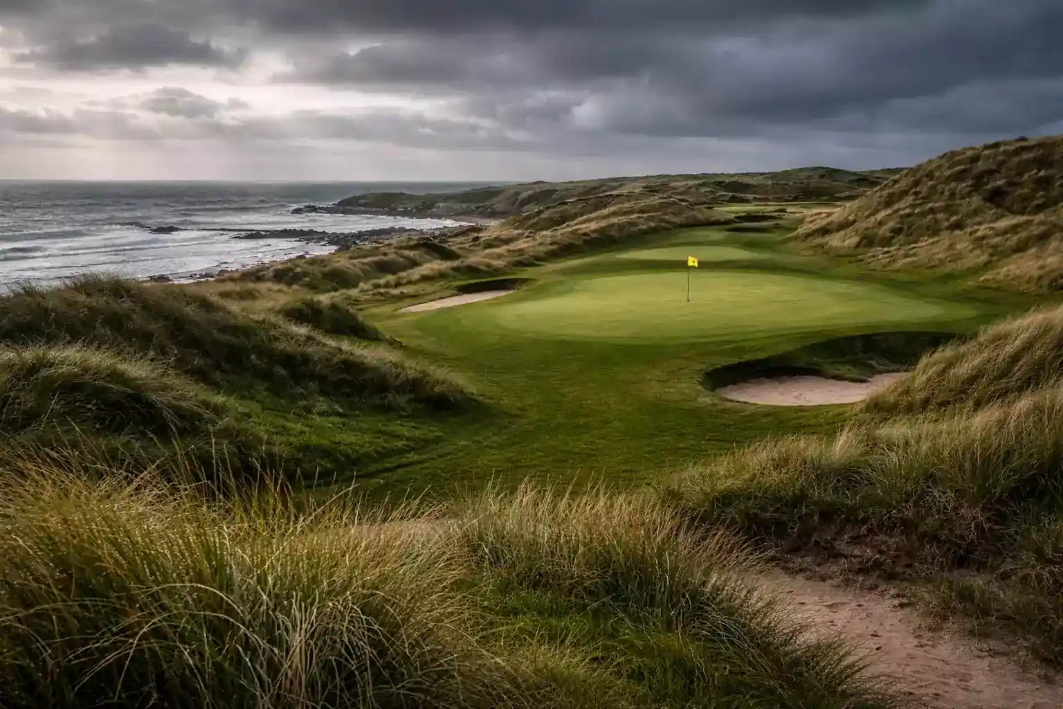 Typischer Links-Golfplatz an der Küste mit bewölktem Himmel und Wind